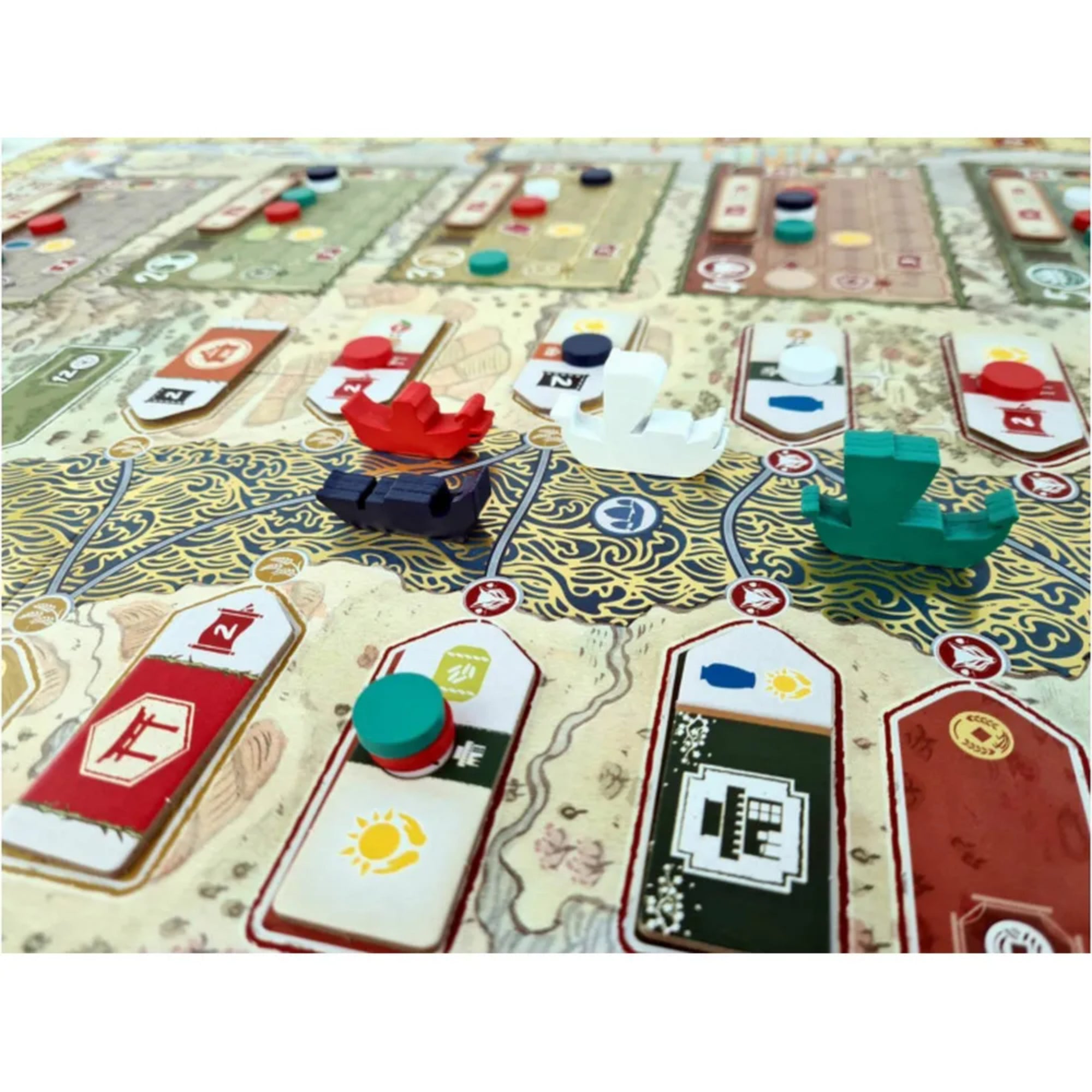 Közeli kép az Aranyfolyó társasjáték fa hajóiról és színes korongjairól a játéktáblán, a folyón és városrészek között mozogva.