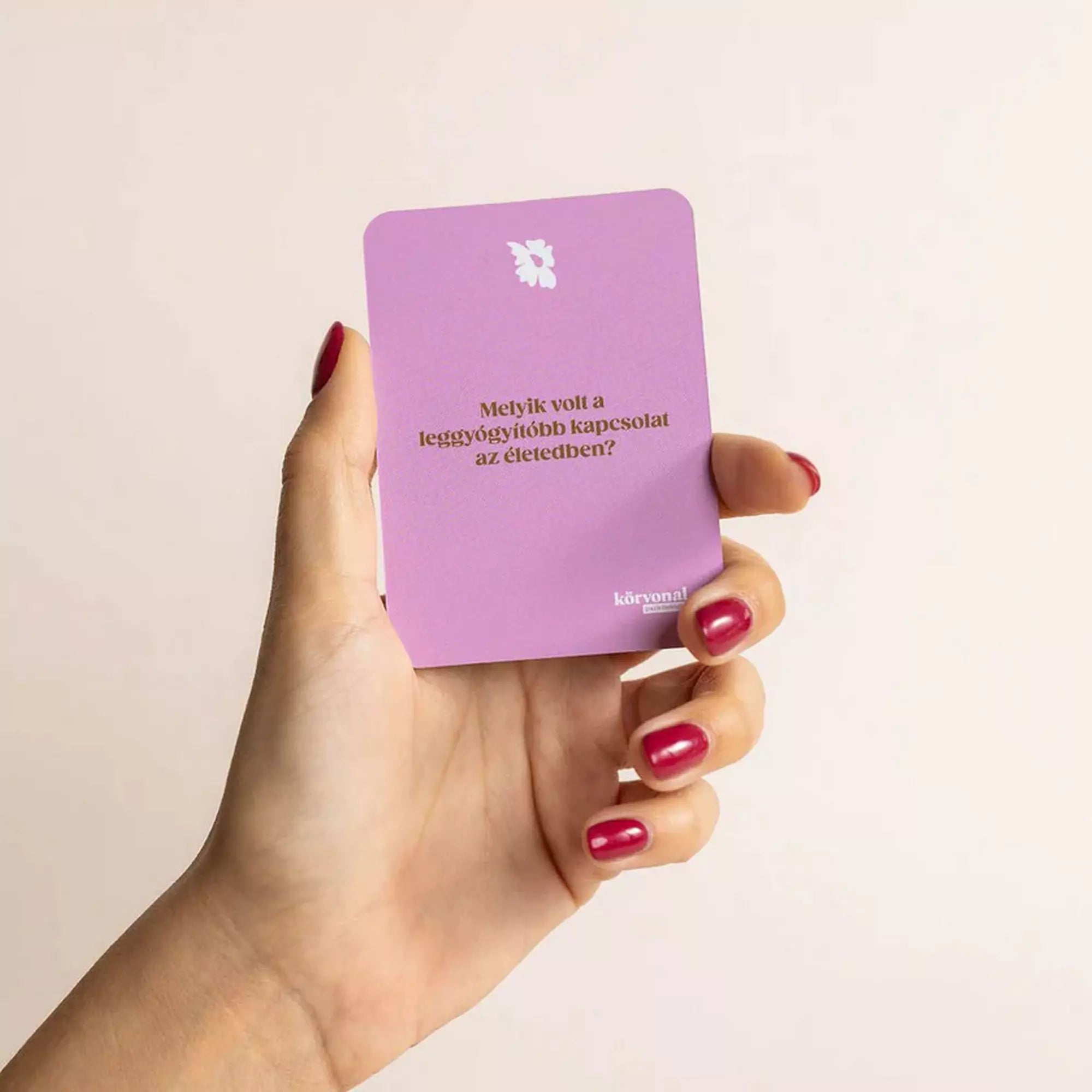 Egy kéz rózsaszín Terápiás beszélgetések kártyát tart, rajta az alábbi kérdéssel: „Melyik volt a leggyógyítóbb kapcsolat az életedben?”