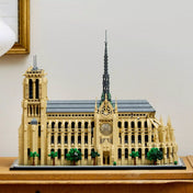 A LEGO Architecture Notre-Dame de Paris (21061) készlet modellje kiállítva egy polcon, oldalnézetből, elegánsan berendezett szobabelsőben.