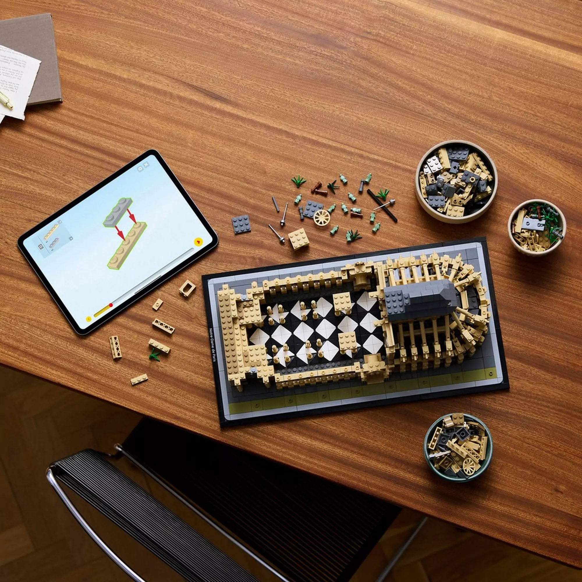 LEGO Architecture Notre-Dame de Paris (21061) modell részlegesen megépítve egy asztalon, táblagéppel és szétválogatott elemekkel körülvéve.