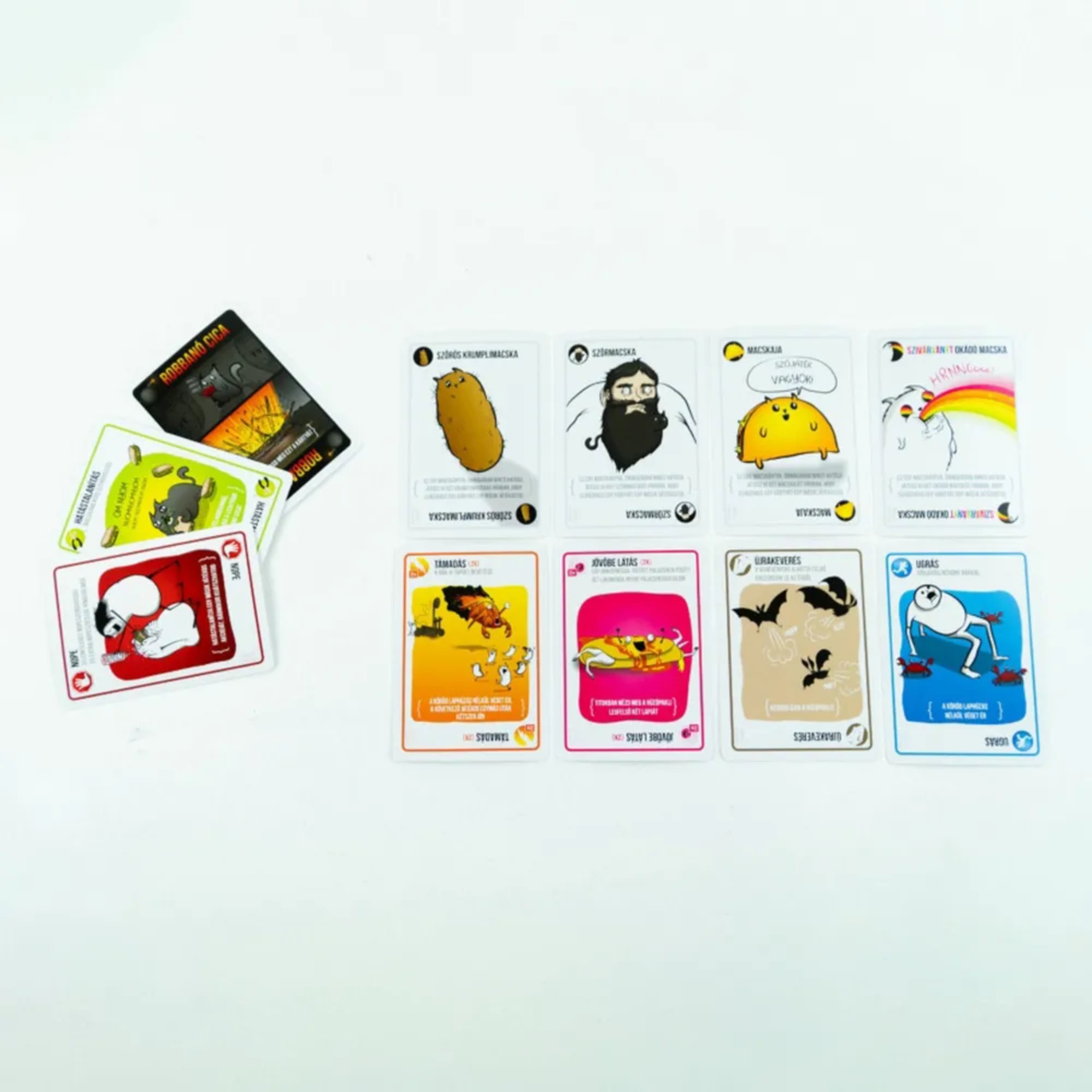 A képen a Robbanó Cicák Mini társasjáték egy válogatott kártyakészlete látható közelebbről. A színes és humoros grafikák azonnal magukra vonják a figyelmet – bal oldalon a rettegett „Robbanó Cica” kártyák látszanak, amelyek elkerülése a játék célja. Jobbra tőlük változatos akciókártyák sorakoznak, például a „Színes krumplimaszka”, a „Szomócica” és az „Űrkártevés”, melyek mind különleges képességeket biztosítanak a játékosoknak.