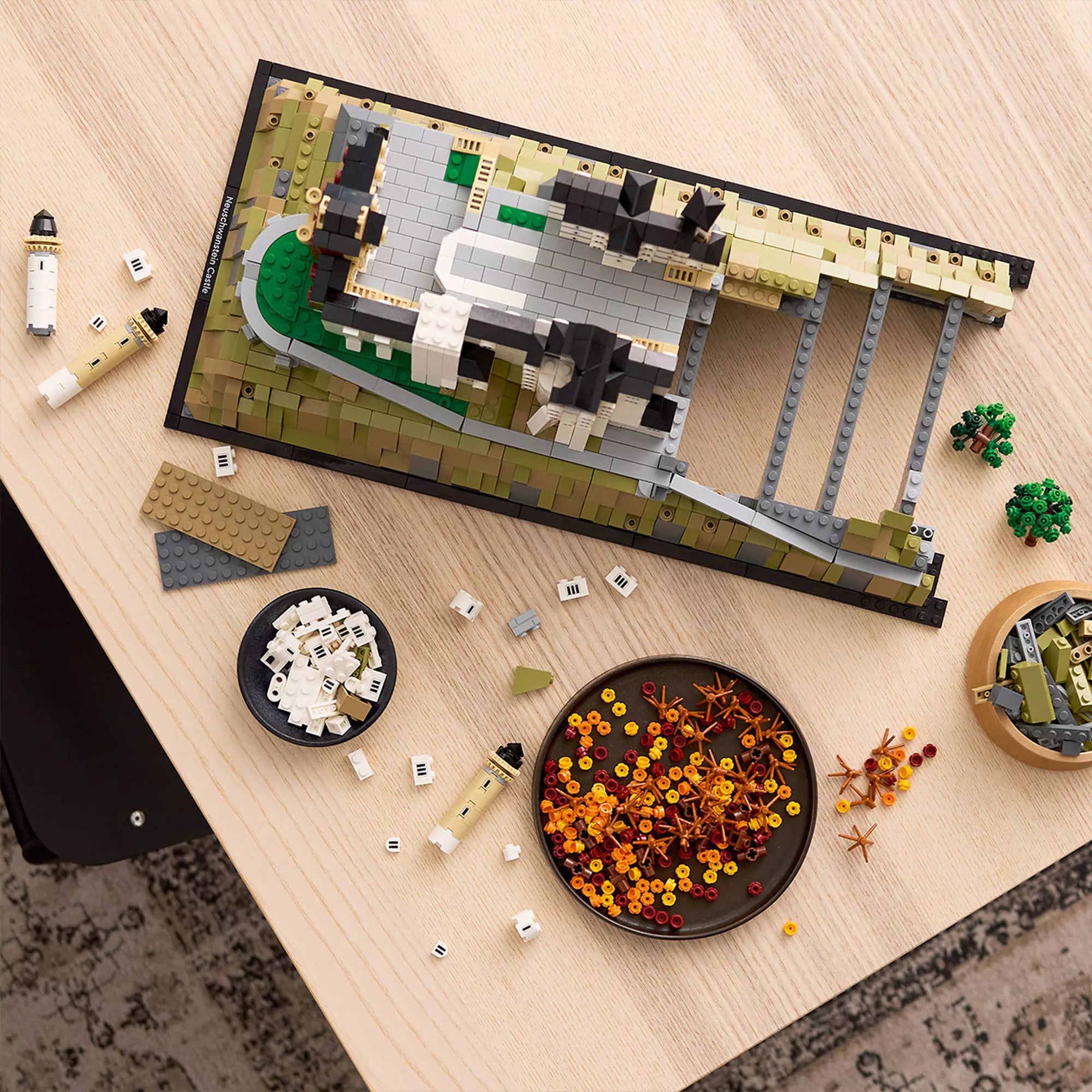 LEGO Architecture: Neuschwanstein kastély (21063) építés közben, LEGO elemekkel és részletes alappal az asztalon.
