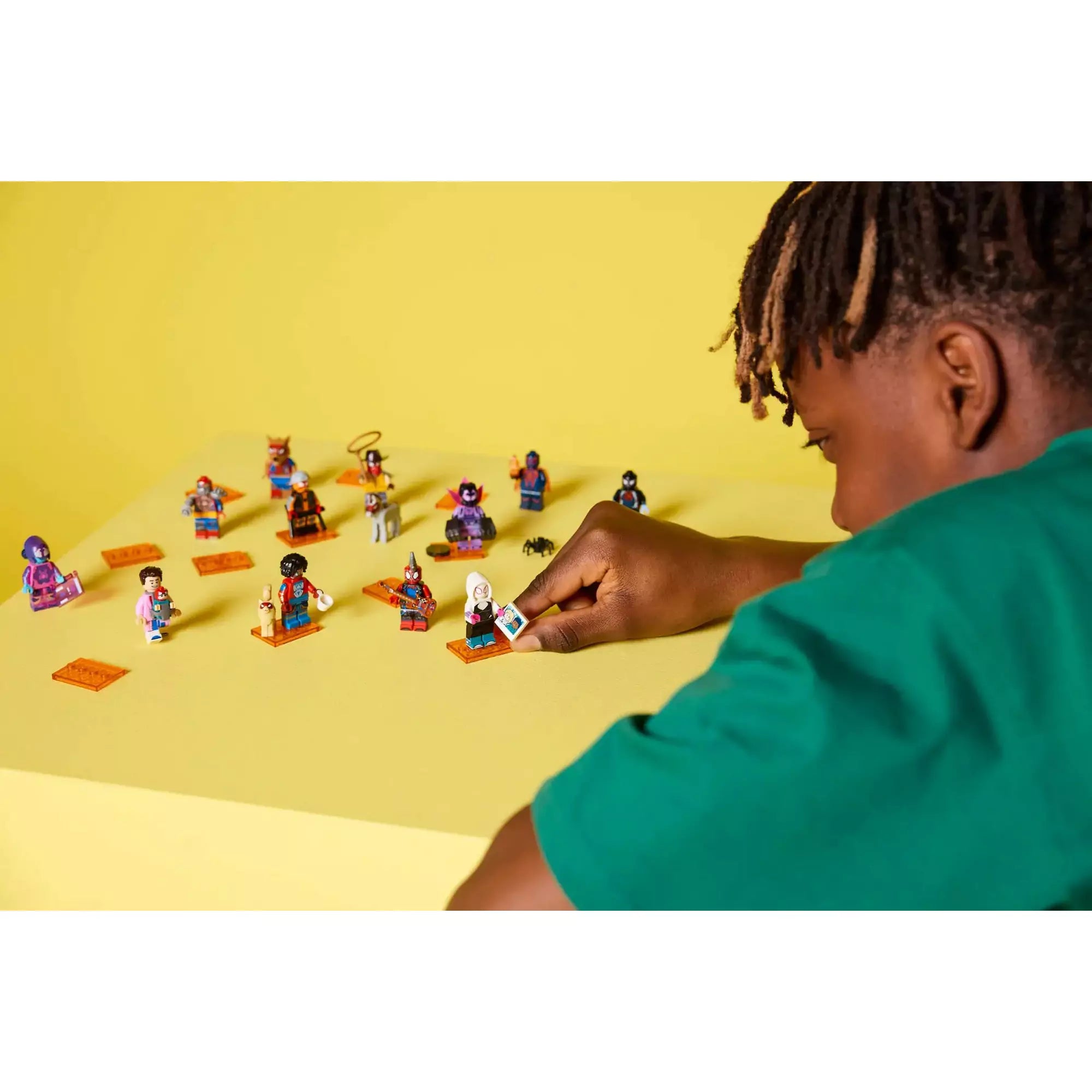 Gyerek a LEGO Spider-Man: A Pókverzum minifigurákkal játszik, köztük Spider-Gwen és más ikonikus karakterekkel.