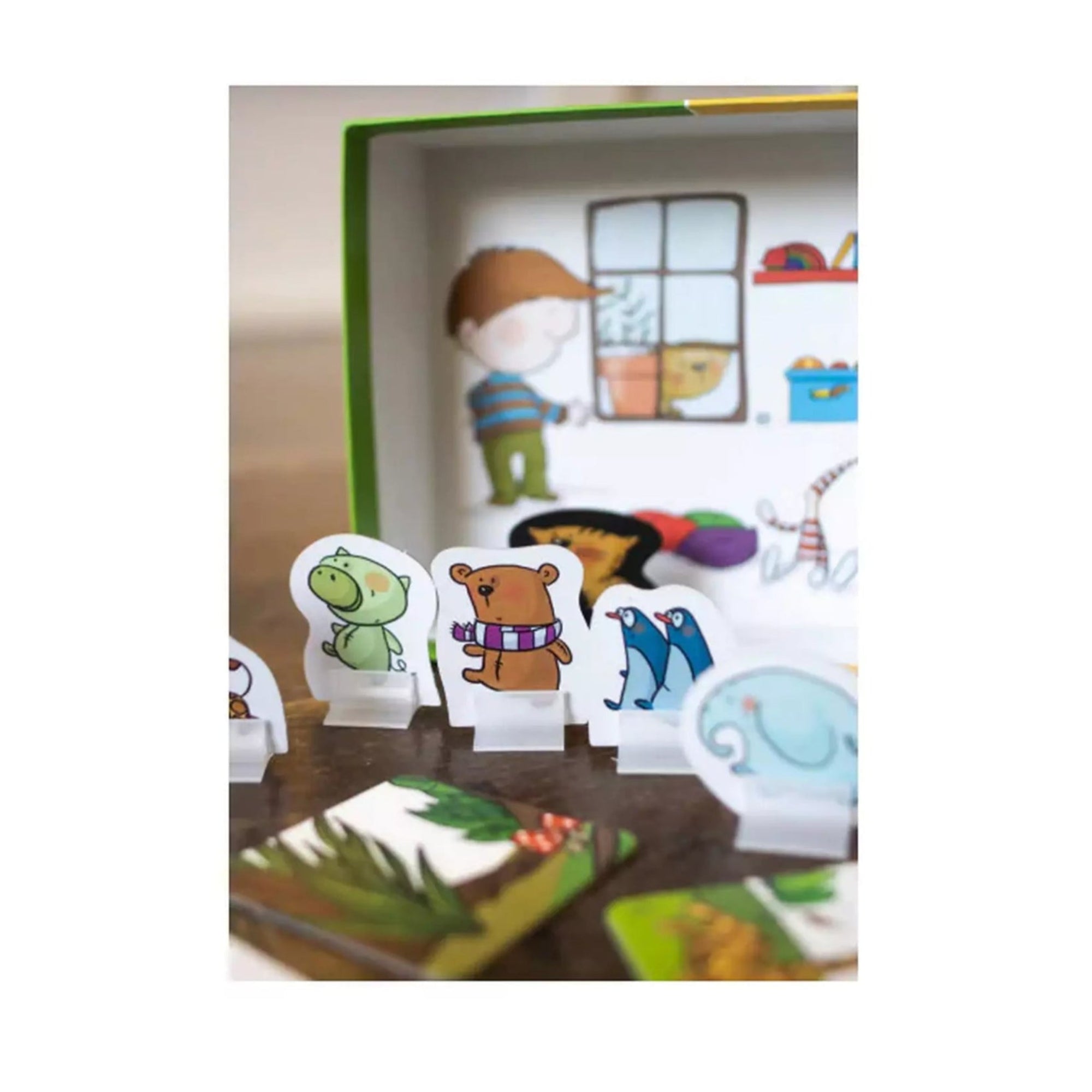 Maszat és az elveszett plüssök társasjáték doboza belülről, előtérben aranyos, színes állatfigurák műanyag talpakon – például egy sálas mackó, egy kis zöld dínó és egy elefánt.