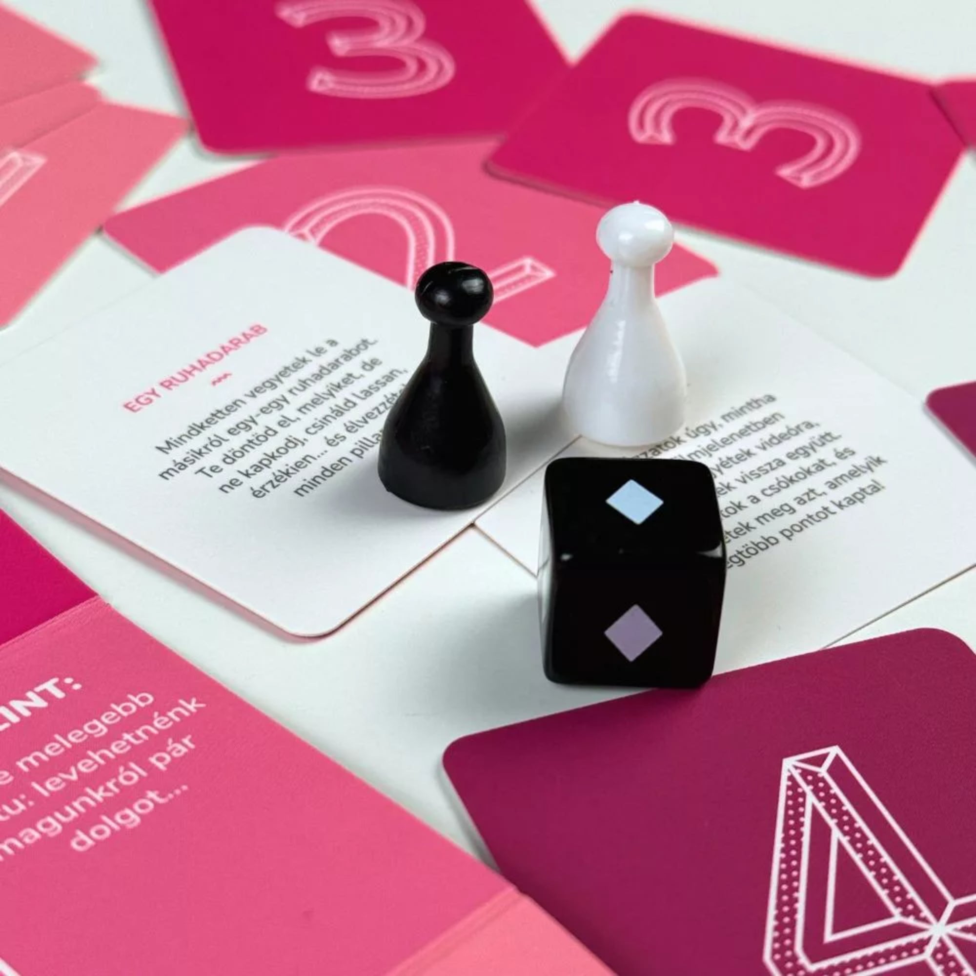 69 – Páratlan játék pároknak játékelemek, fekete és fehér bábuk, dobókocka és tematikus kártyák páros felnőtt társasjátékhoz.