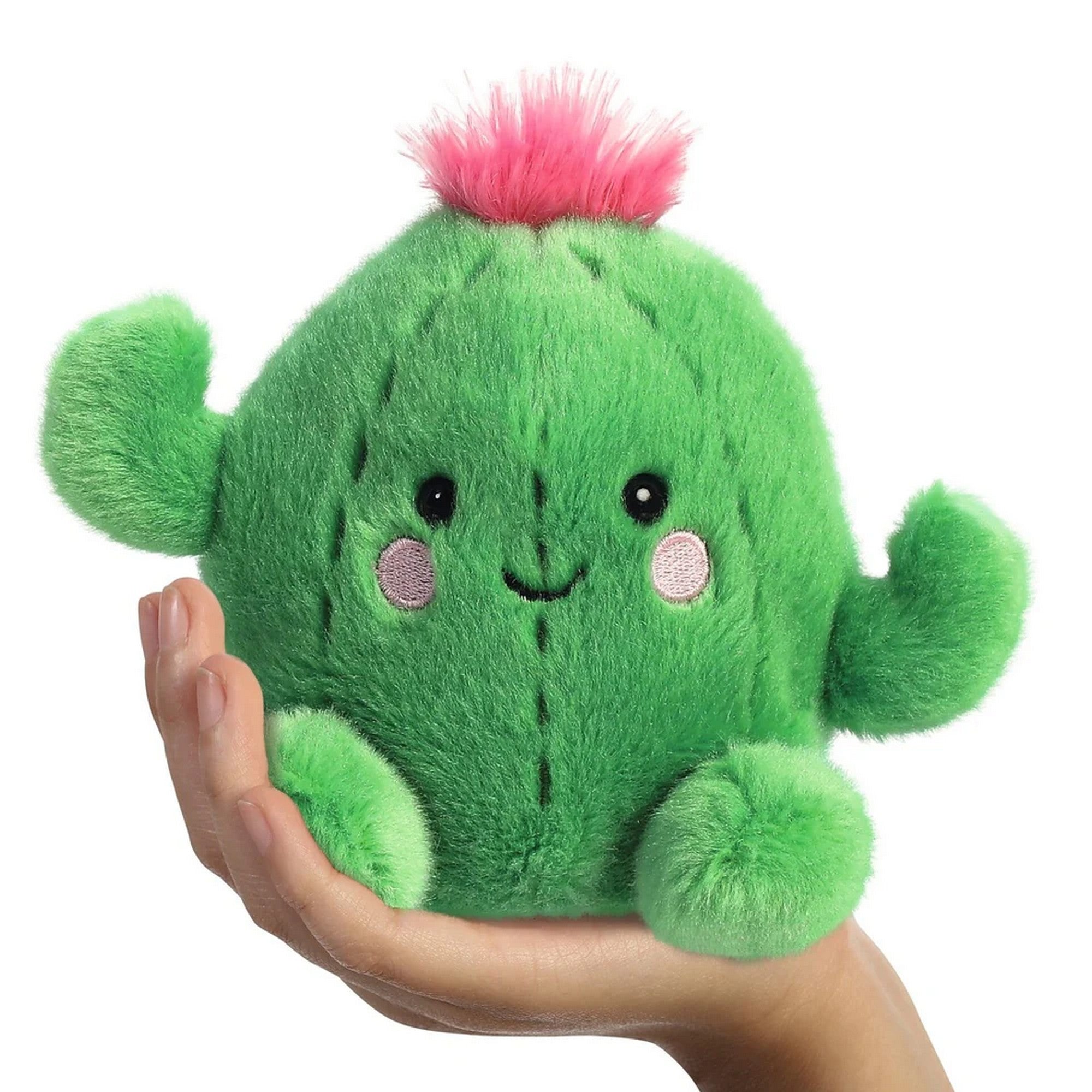 Kaktusz formájú plüss játék kézben tartva, mosolygós arccal, rózsaszín pofikkal és puha, bolyhos felületű anyagból készült aranyos kialakítással