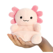 Rózsaszín axolotl plüss játék kézben tartva, mosolygós arccal, fekete szemekkel és puha, selymes tapintású anyagból készült aranyos kialakítással