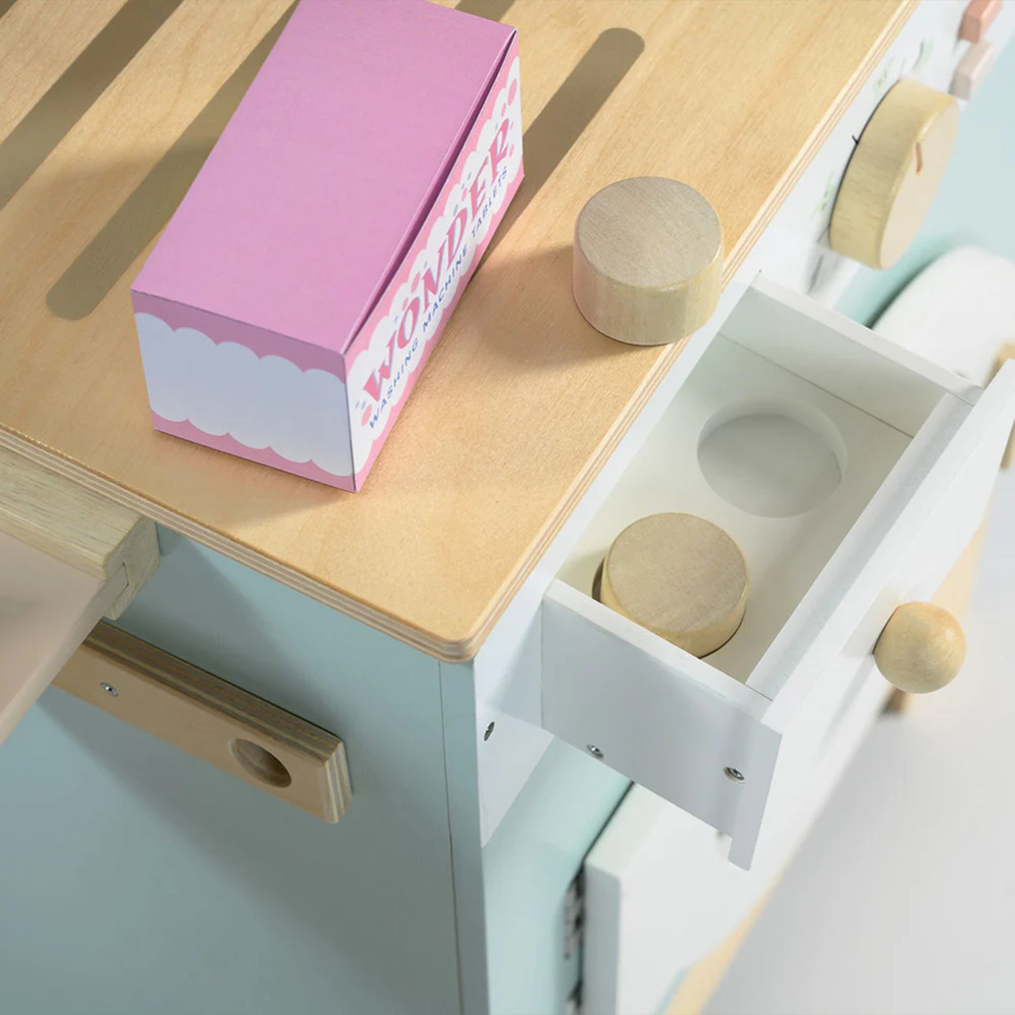 A Tender Leaf fa mosoda részlete, nyitott fiókkal és fa mosószeres dobozokkal, a tetején rózsaszín “Wonder” feliratú kartondoboz látható.