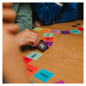 Hitster társasjáték akció közben: játékos QR-kódos kártyát húz és próbálja helyesen elhelyezni a zenei idővonalon az évszámos lapok között.