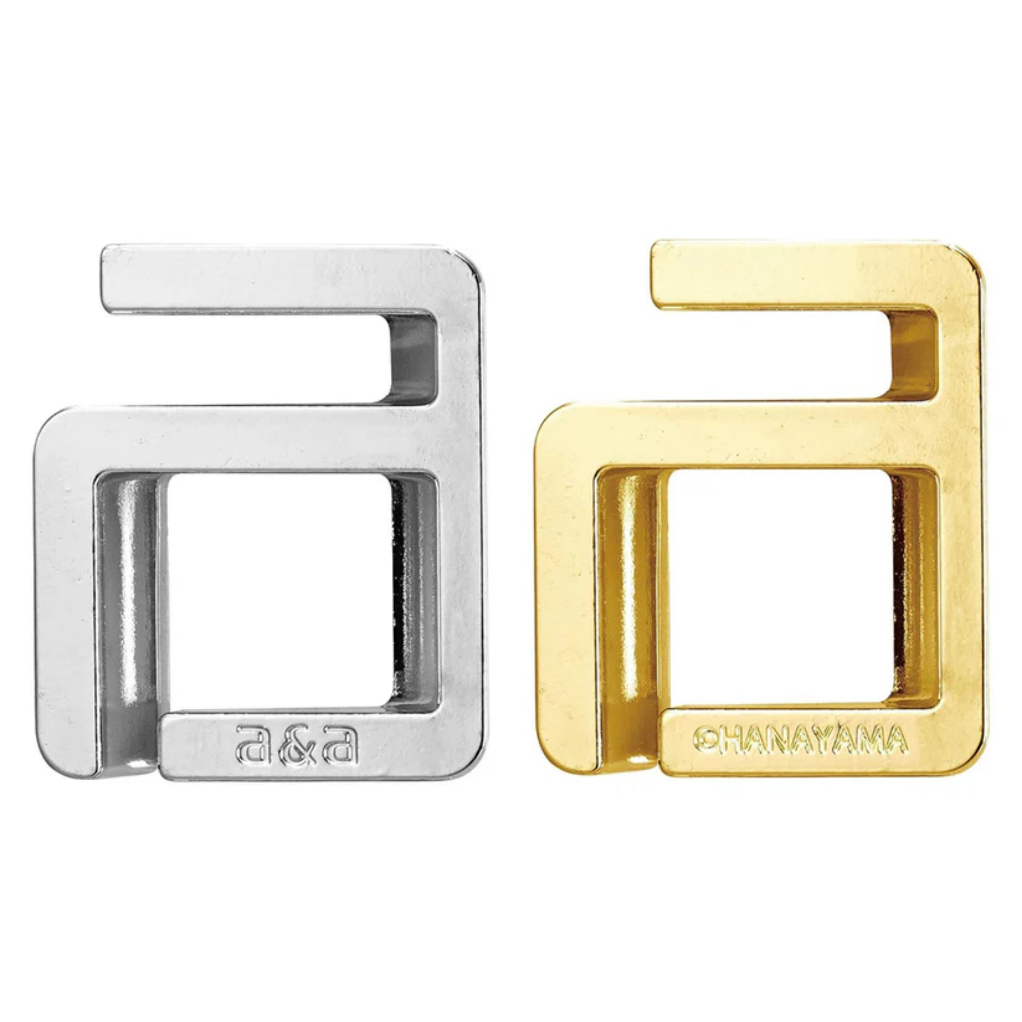 A Huzzle Cast A&A két darabra szedve: egy ezüst és egy arany színű „a” betűre emlékeztető fém elem, amelyek precízen illeszkednek egymásba a kirakó megoldása során.