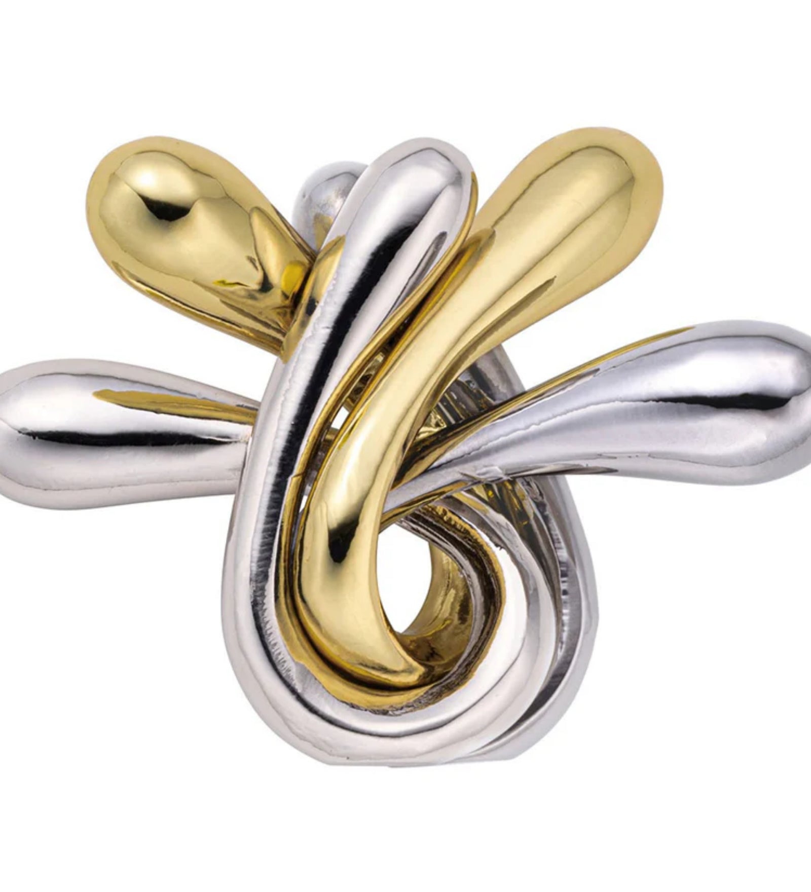 Fényes, összefonódott arany és ezüst színű fém elemekből álló, organikus formájú logikai játék, a Huzzle Cast RIPPLE, amelynek sima, csepp alakú végei elegánsan tekerednek egymásba.