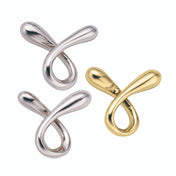 A Huzzle Cast RIPPLE három különálló darabja: két ezüst és egy arany színű, hurkolt, sima felületű fém alkatrész, amelyek együtt egy összetett, térbeli kirakót alkotnak.
