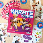 Karate Nagyik társasjáték komponensek felülnézetben, kártyák és zsetonok szétszórva a doboz körül.