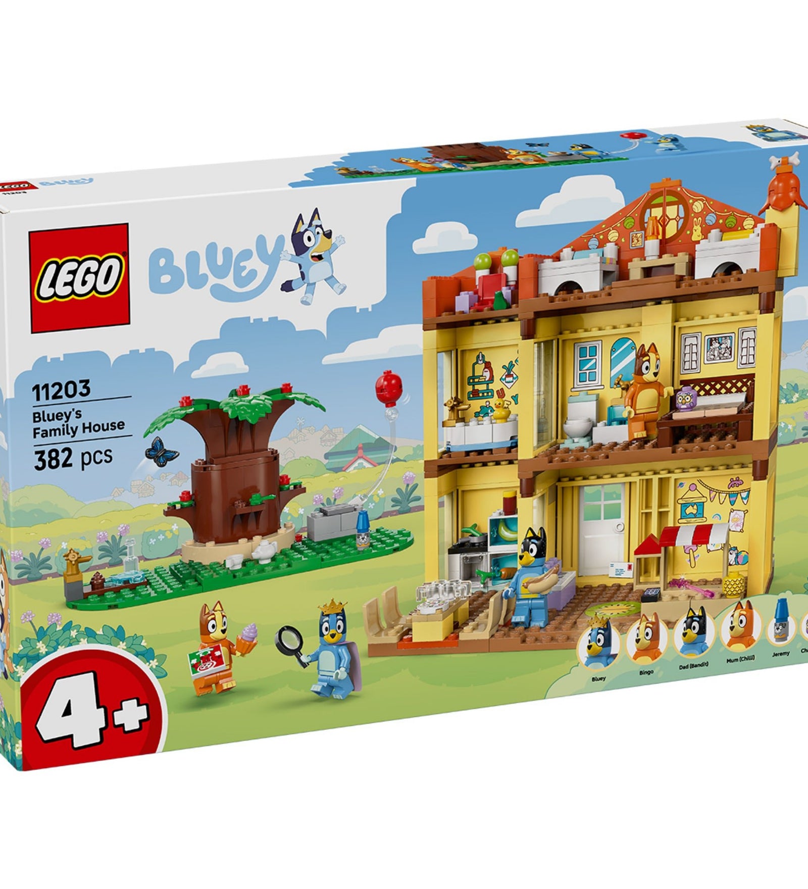 Közelről fotózott LEGO Bluey családi háza doboz, amelyen a sárga piros tetős ház látható nyitott oldallal, Bluey és Bingo játszanak az udvaron, mellette fa és piros lufi. A dobozon feltüntetett információ: 4+ korosztály, 382 darabos, a szereplők nevei is megjelennek.