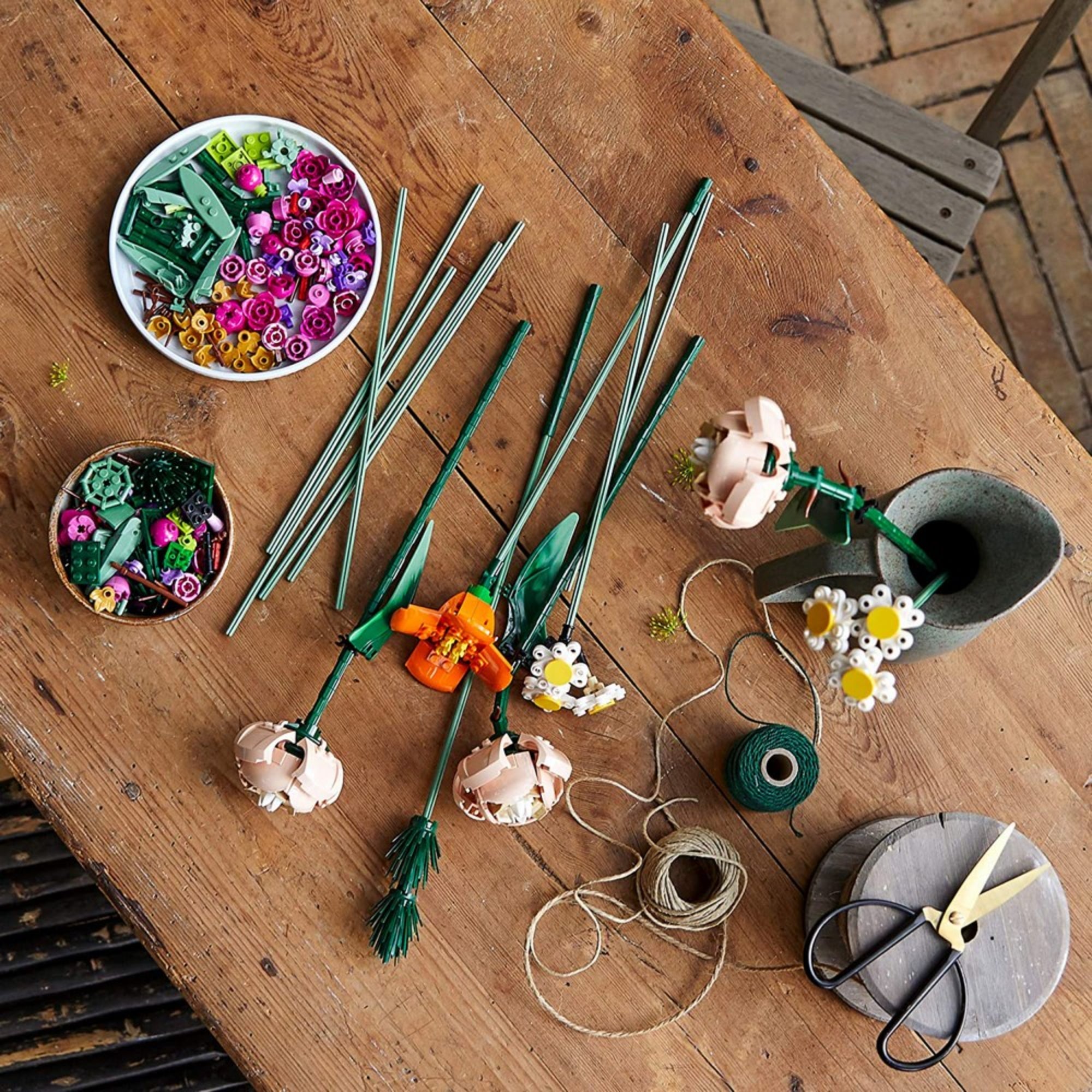 LEGO Flower Bouquet (10280) szett különböző virágdarabokkal egy fából készült asztalon szétszórva.