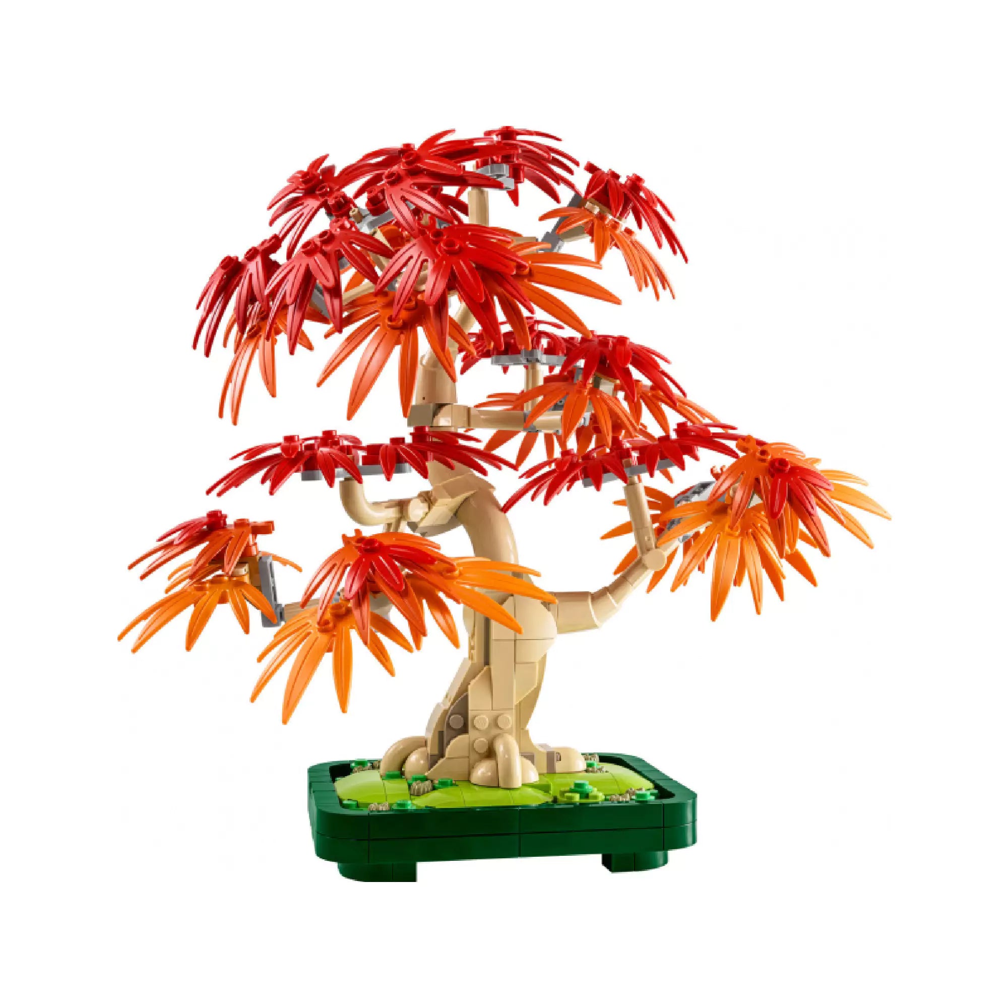 A japán juharfa LEGO-ból épített részletei látszanak közelről. A hajlított barna törzs természetes, organikus formát alkot, a levelek szélesen elterülnek, mintha egy valódi fa lenne. A zöld alapon kis díszítőelemek egészítik ki az összhatást.