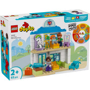 A LEGO DUPLO Első látogatás az orvosnál (10449) doboza, amely egy színes, orvosi rendelőt ábrázoló játékkészletet mutat be, különleges érzelemkerékkel.

