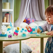 LEGO DUPLO Disney Jégvarázs Elsa és Olaf kreatív építőkészlet (10462) használat közben, kisgyermek által épített Jégvarázs jelenetekkel, Elsa és Olaf figurákkal egy játékasztalon.