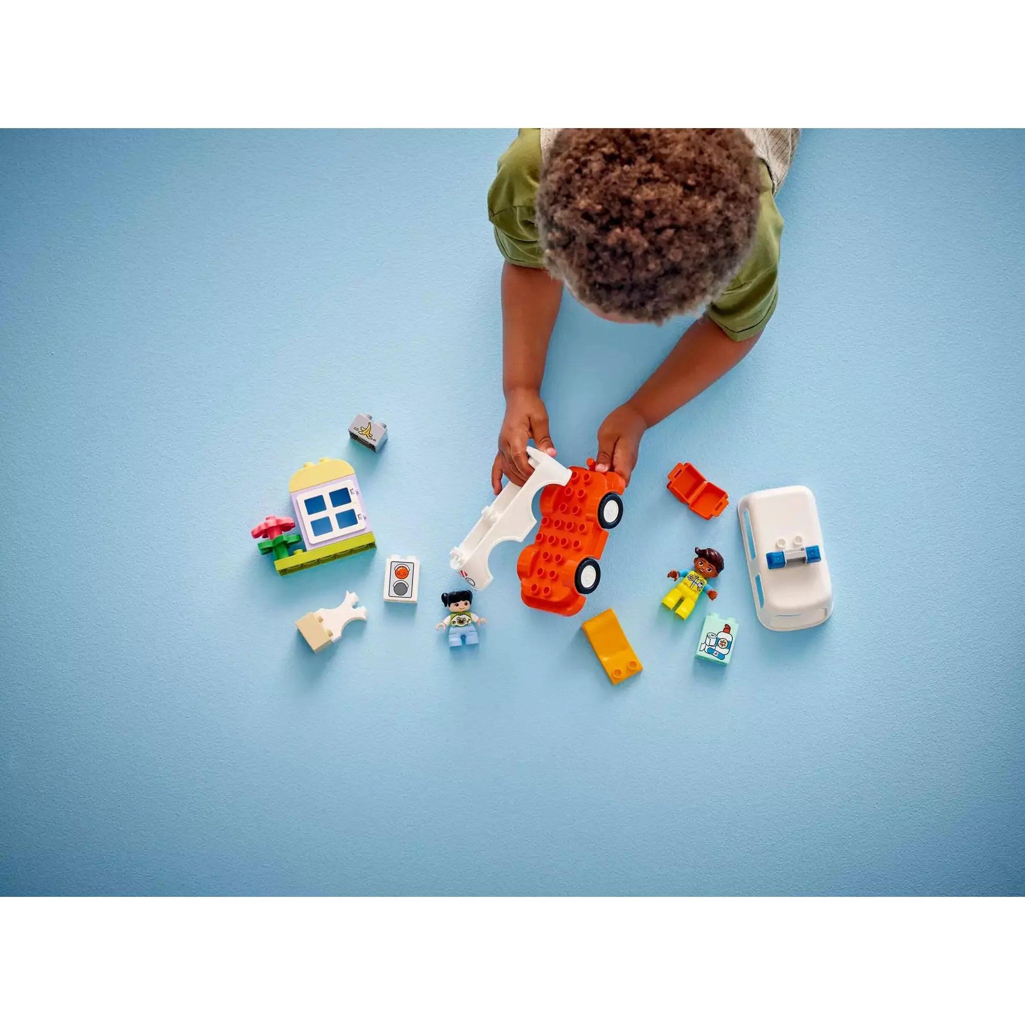 Egy gyerek összeszereli a LEGO Duplo Mentőautó és mentősofőr (10447) készlet különböző részeit, fejlesztve a finommotoros készségeit.