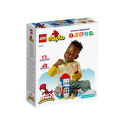 Egy kisfiú játszik a LEGO DUPLO Pókember háza (10995) készlettel; a doboz hátoldalán a készlet előnyei, a játszva tanulás ikonokkal, valamint a Spidey and His Amazing Friends logó látható.