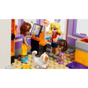 LEGO minifigurák a Heartlake City közösségi konyhában: Leo egy rendelőkijelzőn keresztül vesz fel rendelést Matildétől, miközben egy fehér macska játékosan figyeli őket.