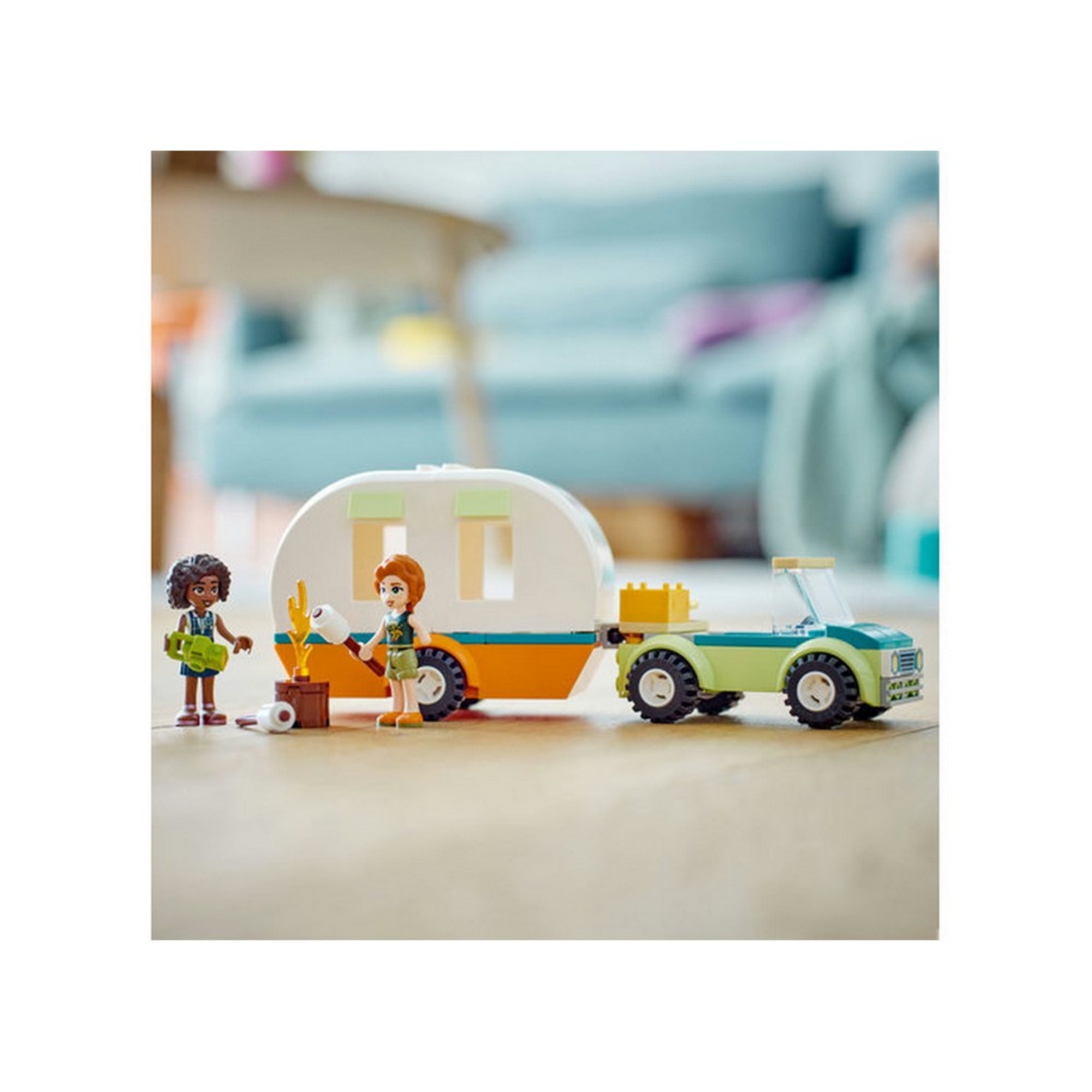 LEGO Friends 41726 Kempingezés lakókocsival – a szett felépítve egy otthoni háttér előtt, ami valós játékhelyzetet idéz. Autumn és Aliya minifigurák a tábortűz körül állnak, a lakókocsi és terepjáró mögöttük. A természetes megvilágítás kiemeli a részleteket és a játékélmény valóságosságát.