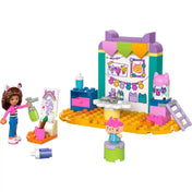 A LEGO Gabby's Dollhouse Barkácsolás Pici Dobozzal (10795) teljes készlete: barkácsállomás, festékes kiegészítők, rajzállvány, Gabi és Pici Doboz minifigurái élénk színekben.