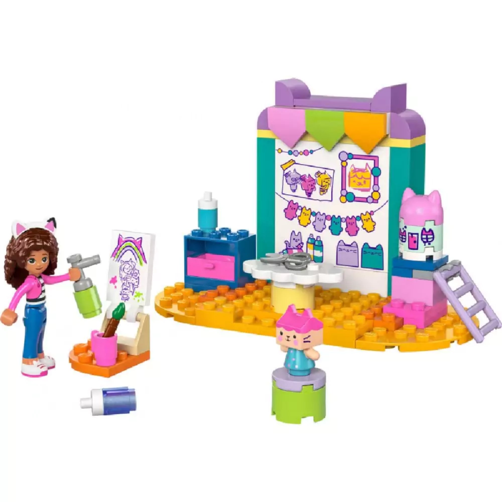 A LEGO Gabby's Dollhouse Barkácsolás Pici Dobozzal (10795) teljes készlete: barkácsállomás, festékes kiegészítők, rajzállvány, Gabi és Pici Doboz minifigurái élénk színekben.