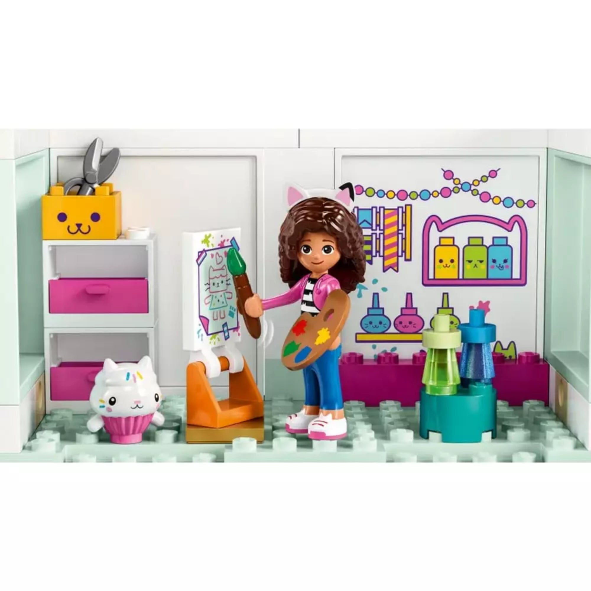 LEGO Gabby babaháza (10788) festőszobája, Gabi figura ecsettel és palettával, egy vásznon macskás festménnyel, vidám kiegészítőkkel.