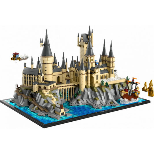 Részletes LEGO modell a Roxfort kastélyról és környezetéről, tengerparti sziklákkal, épületrészekkel, hajóval, valamint repülő motoros járművel a levegőben, világos háttér előtt.