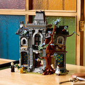 LEGO Icons 11383 Mayor Manor részletgazdag kastélymodellje színes üvegablakokkal, fával és minifigurákkal, faasztalon elhelyezve.