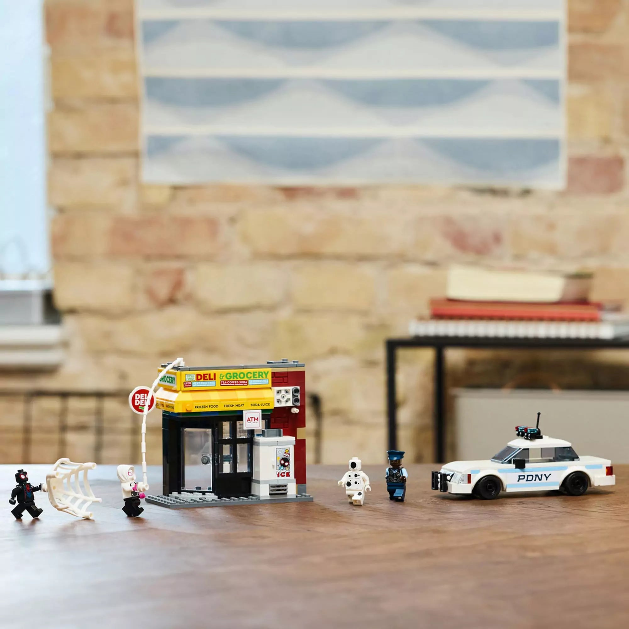 Az asztalon összeállított ,,LEGO Pókverzum: Miles Morales vs. Spot 76311" szett, amely egy boltot, rendőrautót és akciójelenetet ábrázol.