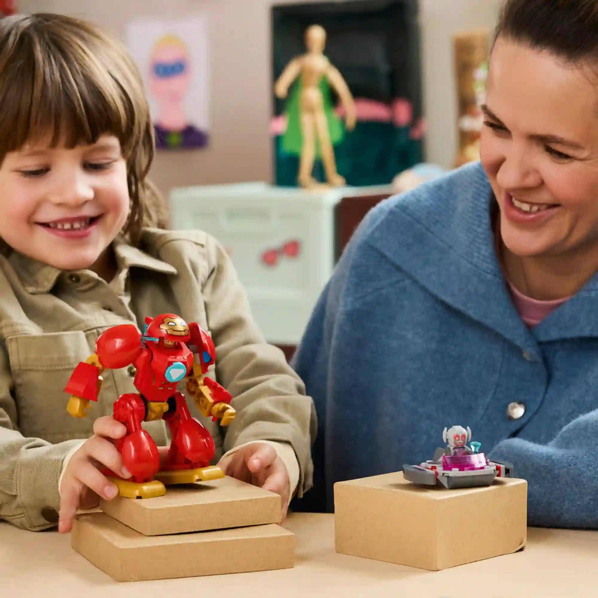 LEGO Marvel Vasember Hulkbuster vs. Ultron (11209) életképen, ahol egy gyermek a megépített piros Hulkbuster páncéllal játszik, miközben Ultron a lebegő platformján látható.