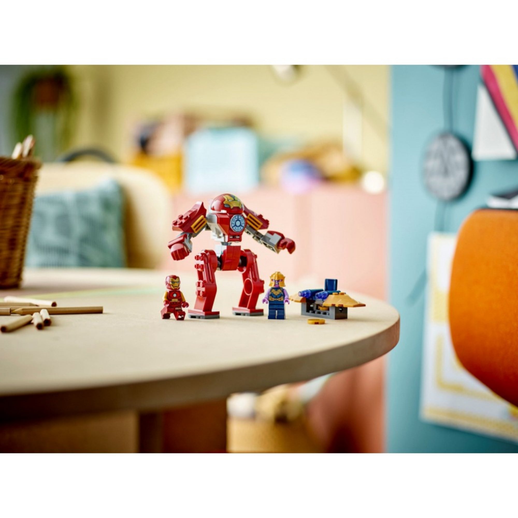 A LEGO Hulkbuster figura kiállítva, dinamikus pózban Thanos minifigurával szemben, harcra készen, díszlet nélküli háttérrel.