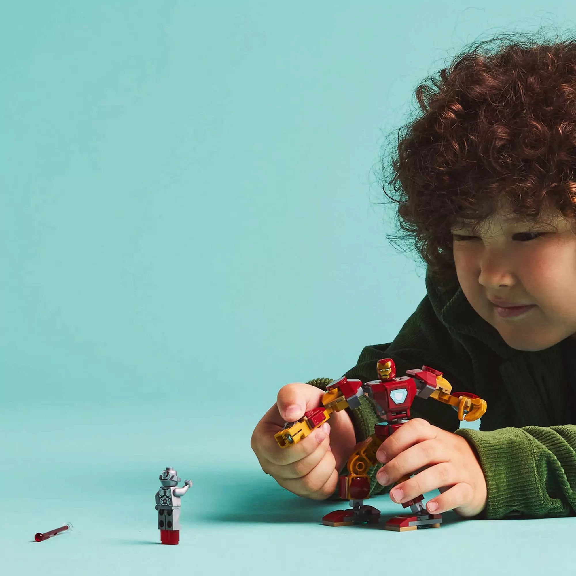 Egy kisfiú játék közben a LEGO Marvel Vasember robottal (76307) és az Ultron minifigurával, epikus küzdelmet szimulálva.