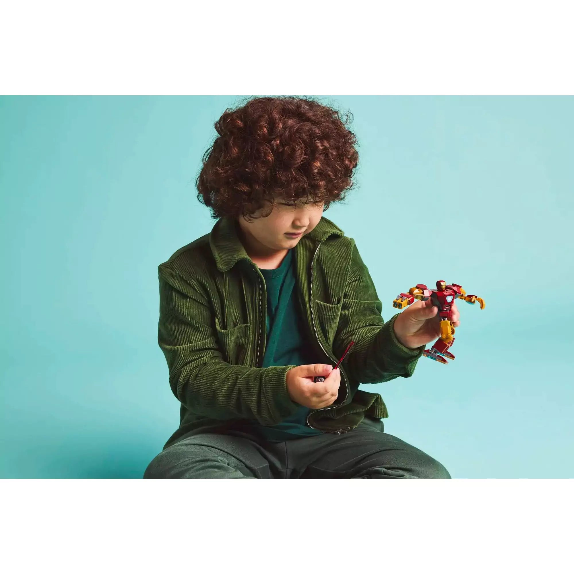  Egy kisfiú a LEGO Marvel Vasember robot vs. Ultron (76307) készlettel játszik, kezében a Vasember robottal és Ultron lézerkardjával.