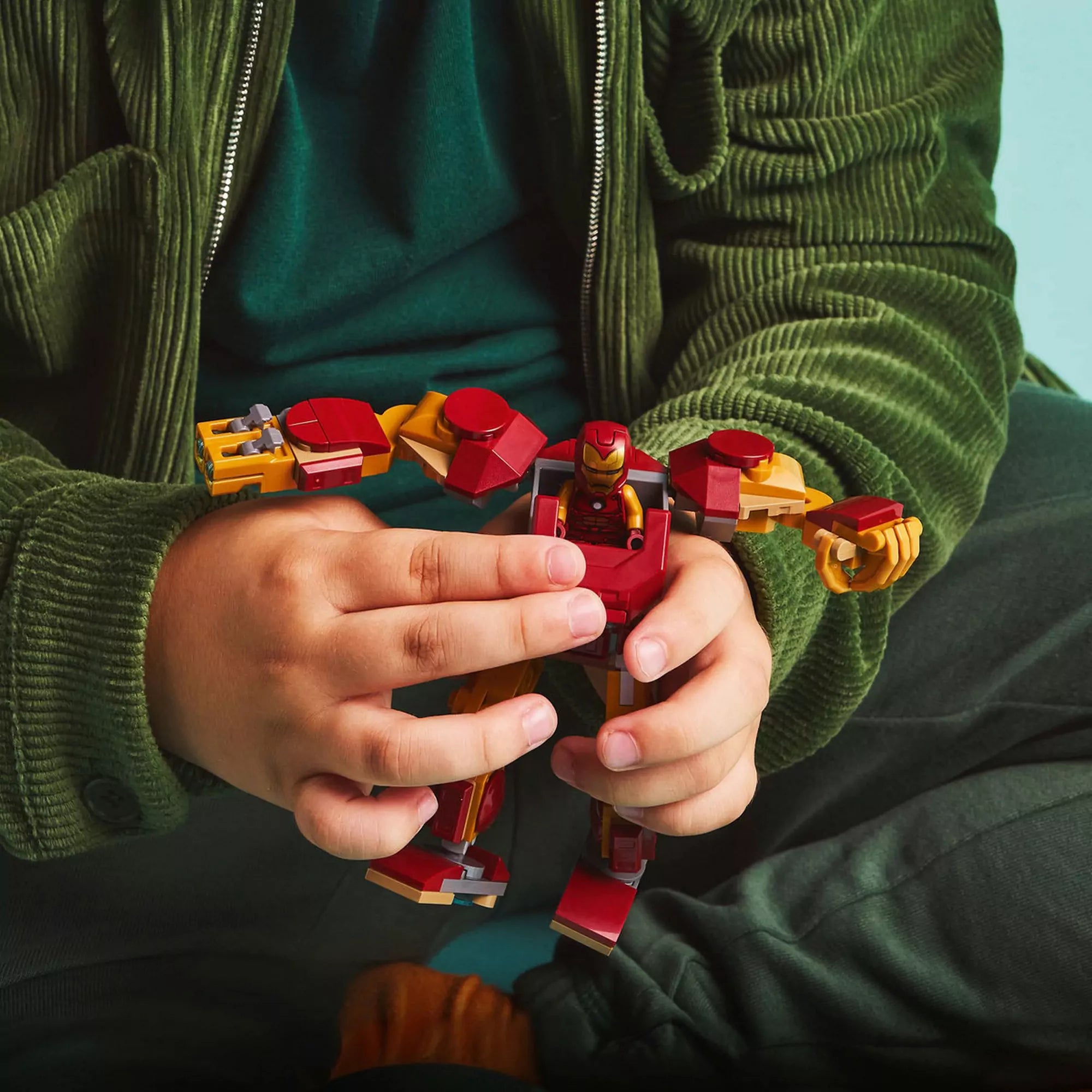 Egy gyermek tartja a LEGO Marvel Vasember robotot (76307), miközben a robot mozgatható karjait állítja.