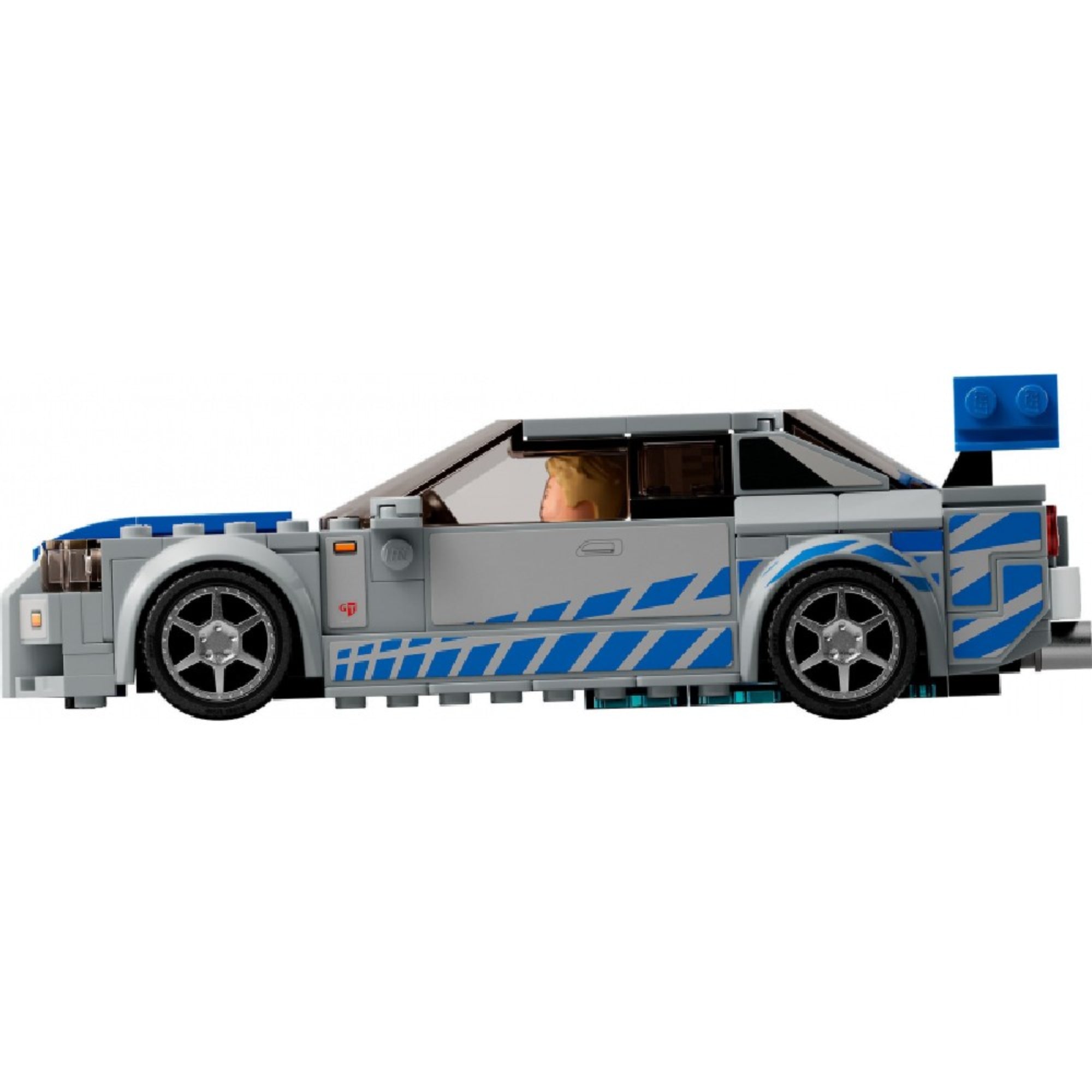 A LEGO 76917 készletből megépített ezüstszürke Nissan Skyline GT-R (R34) oldalnézeti képe, a jellegzetes kék csíkos díszítéssel és a vezetőülésben ülő Brian O’Conner minifigurával.