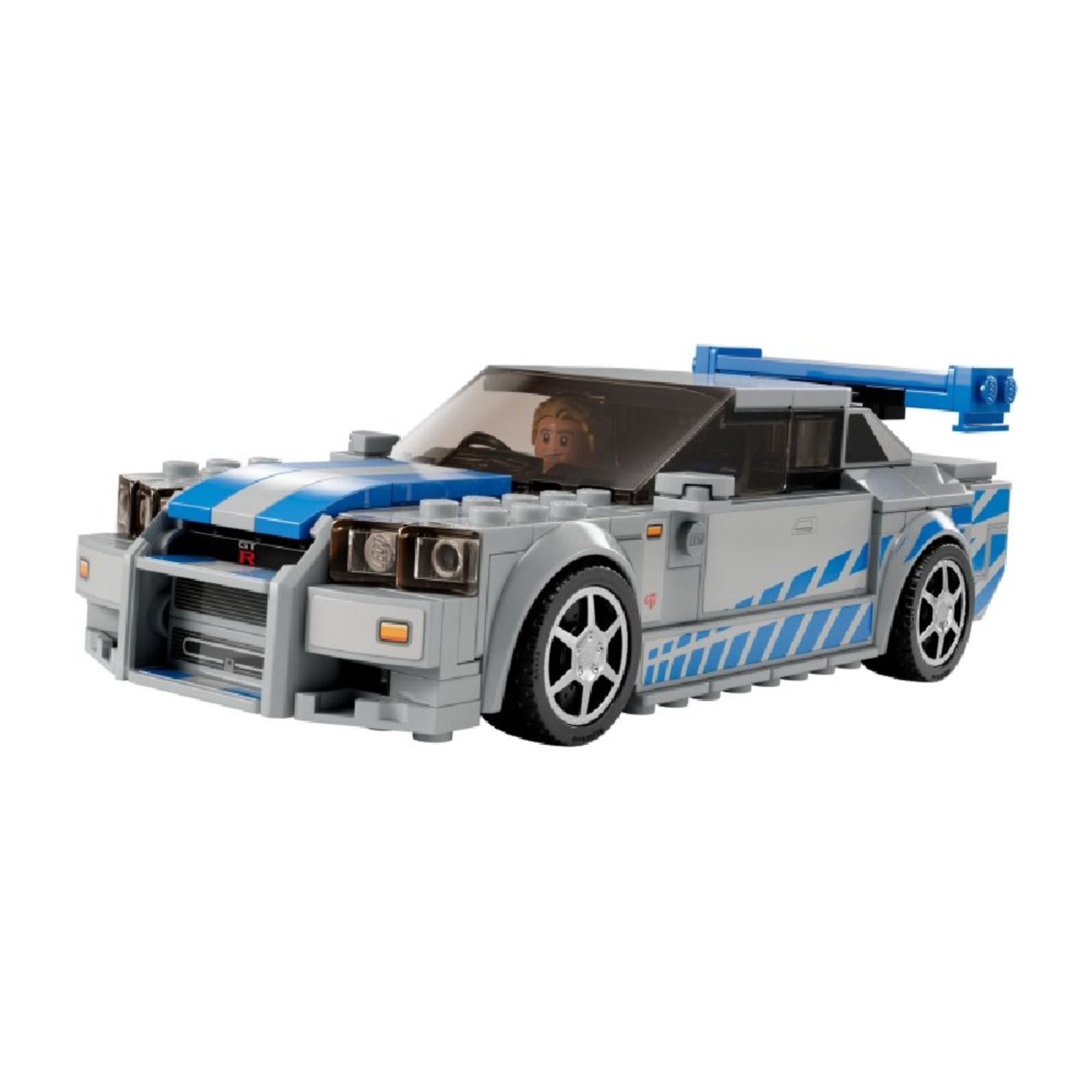 A LEGO Speed Champions Nissan Skyline GT-R (R34) elölnézeti fotója, a volán mögött Brian O’Conner minifigurával, kék-fehér fényezéssel és agresszív hűtőrács kialakítással.