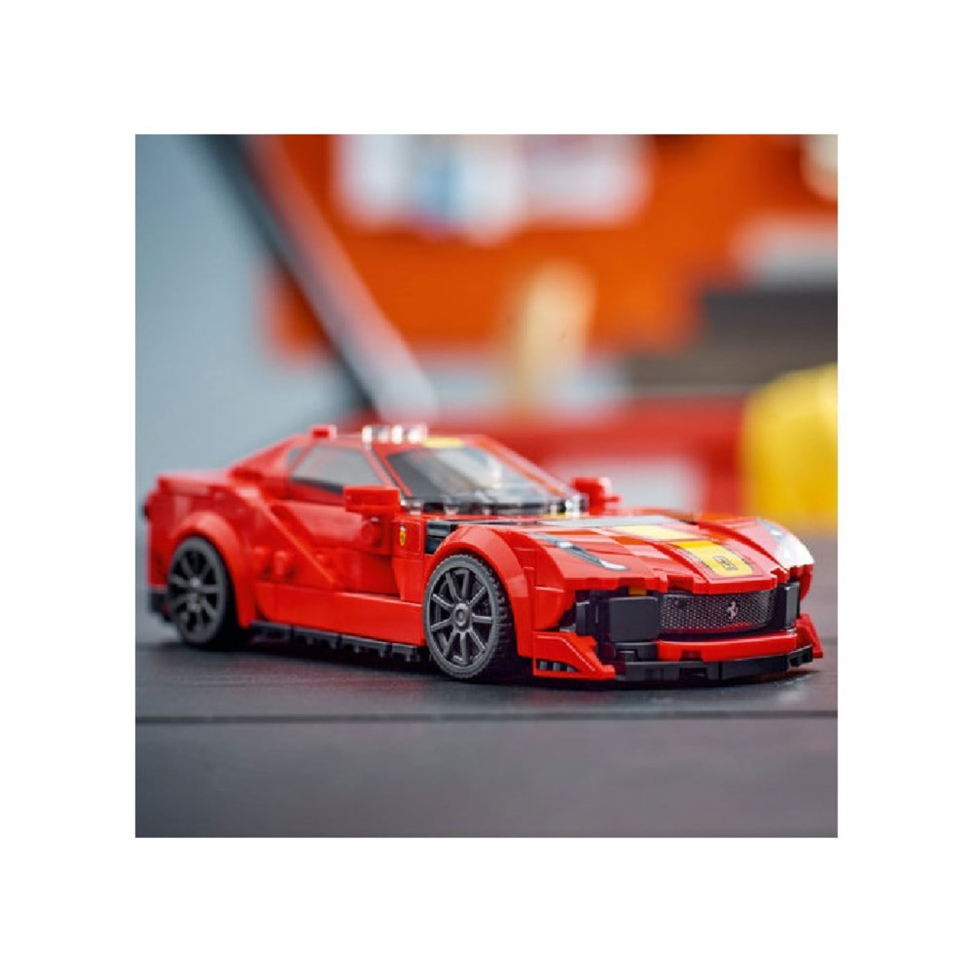 A LEGO Ferrari 812 Competizione elkészült, kiállított állapotban egy sötét felületre helyezve, a modell élénk piros és sárga színeiben.