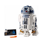A LEGO Star Wars R2-D2 (75308) részletes modellje elölnézetből, mozgatható panelekkel, kihajtható karokkal, mellette információs tábla és egy exkluzív R2-D2 minifigura a Lucasfilm 50. évfordulós talapzaton.