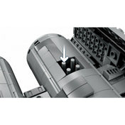A LEGO Star Wars TIE bombázó (75347) készlet bombatároló rekesze nyitott fedéllel, benne négy szürke tartóelem látható, fehér nyíl mutat a működtető mechanizmusra.