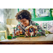 Közelkép arról, ahogy a gyermek a LEGO Super Mario Donkey Kong lombháza kiegészítő szett (71424) Donkey Kong figurájával és Mario karakterével játszik a faház belső terében.