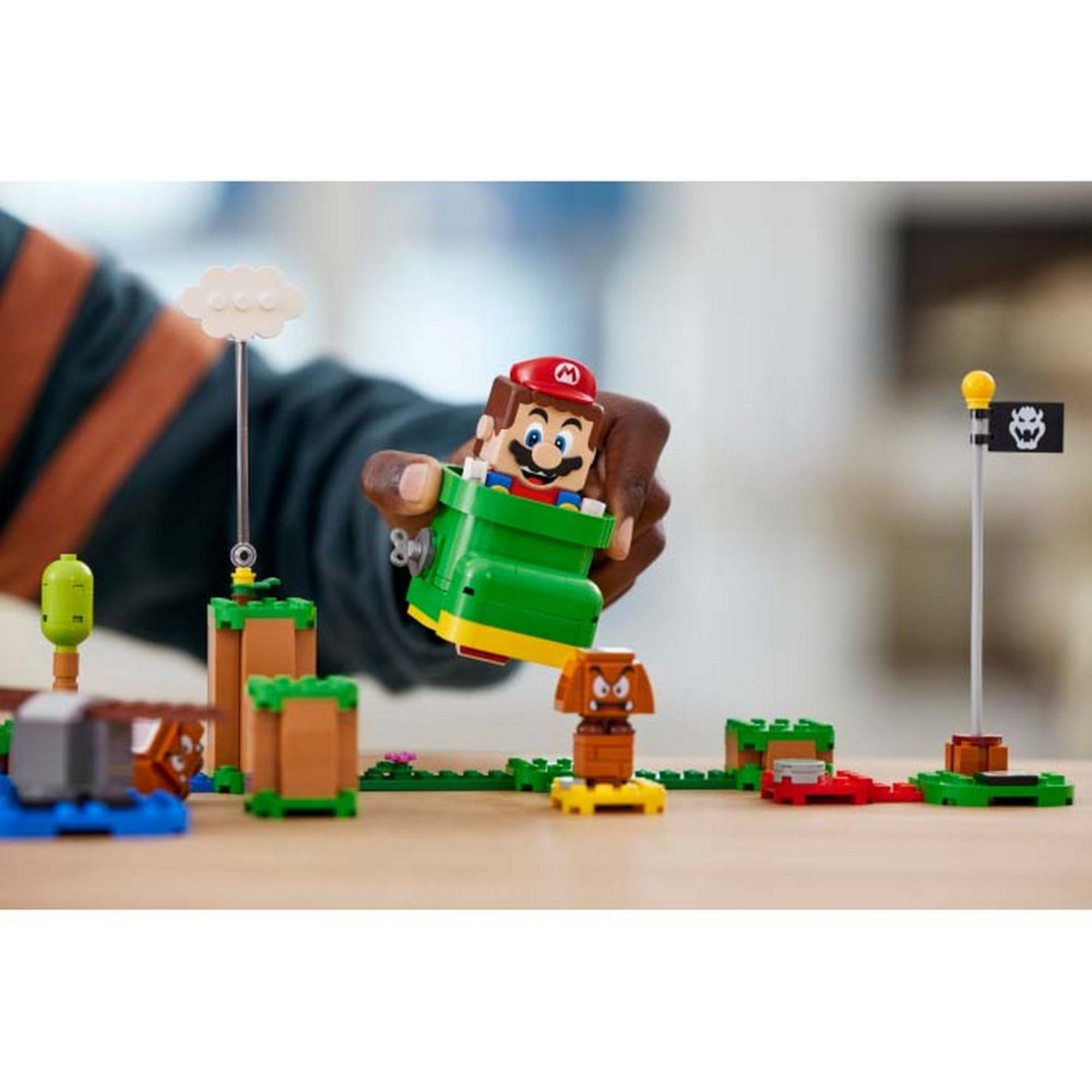 Közelkép a LEGO Super Mario Goomba cipője (71404) játékról, ahol a Mario figura a zöld cipőben ül, és épp a Goombát próbálja eltalálni.