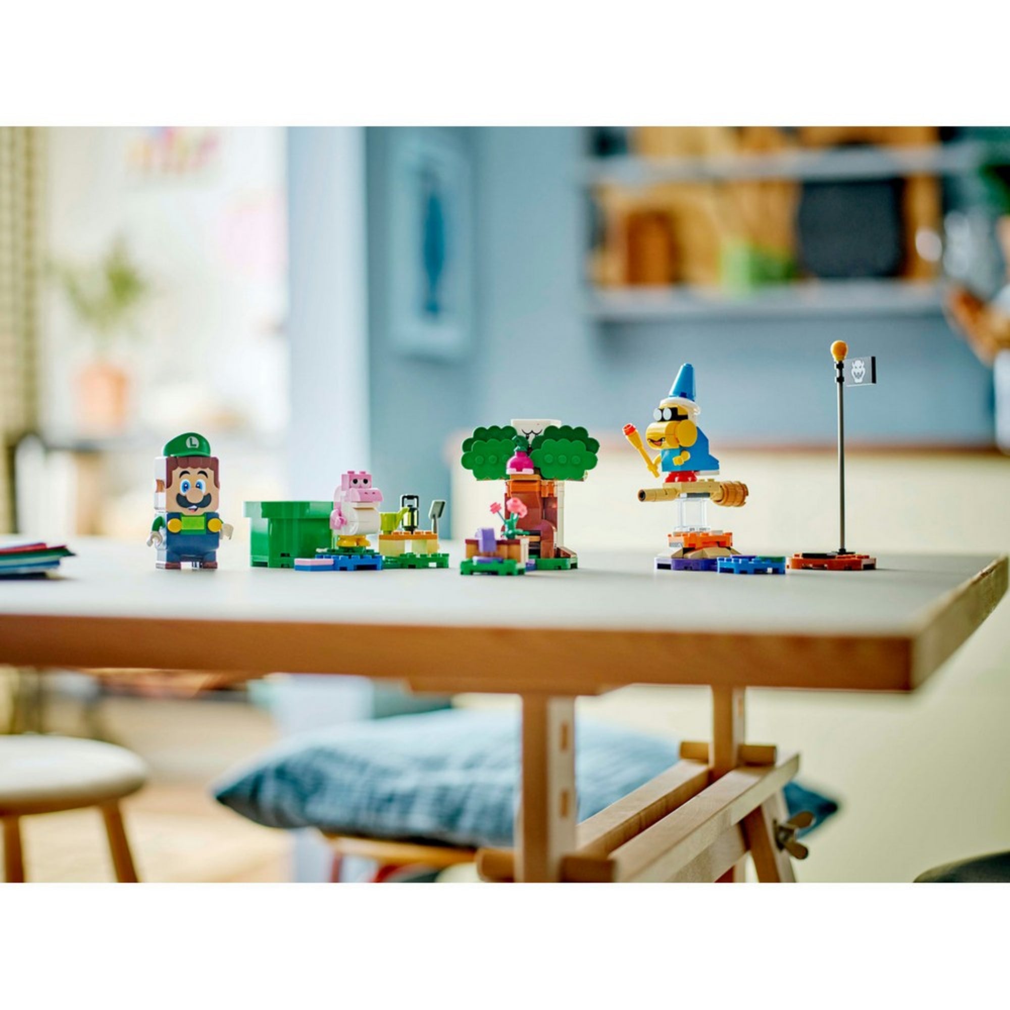 Egy otthoni környezetben lévő asztalon felállítva látható az egész LEGO Super Mario 71440 szett: Luigi, Baby Yoshi, Boo, Kamek és a különböző pályaelemek színes összeállítása.