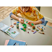 Egy gyermek az asztalnál ülve éppen összeszereli a LEGO Super Mario 71440 szettet, körülötte szétszórva a különböző LEGO elemek, karakterek és az útmutató.