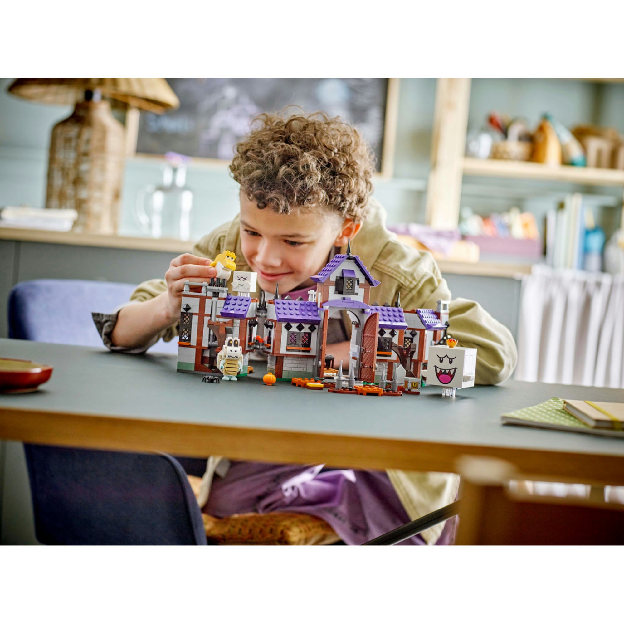 Egy gyermek játszik a LEGO Super Mario King Boo kísértetkastélya (71436) készlettel, miközben a szellemek és figurák életre kelnek a játék során.