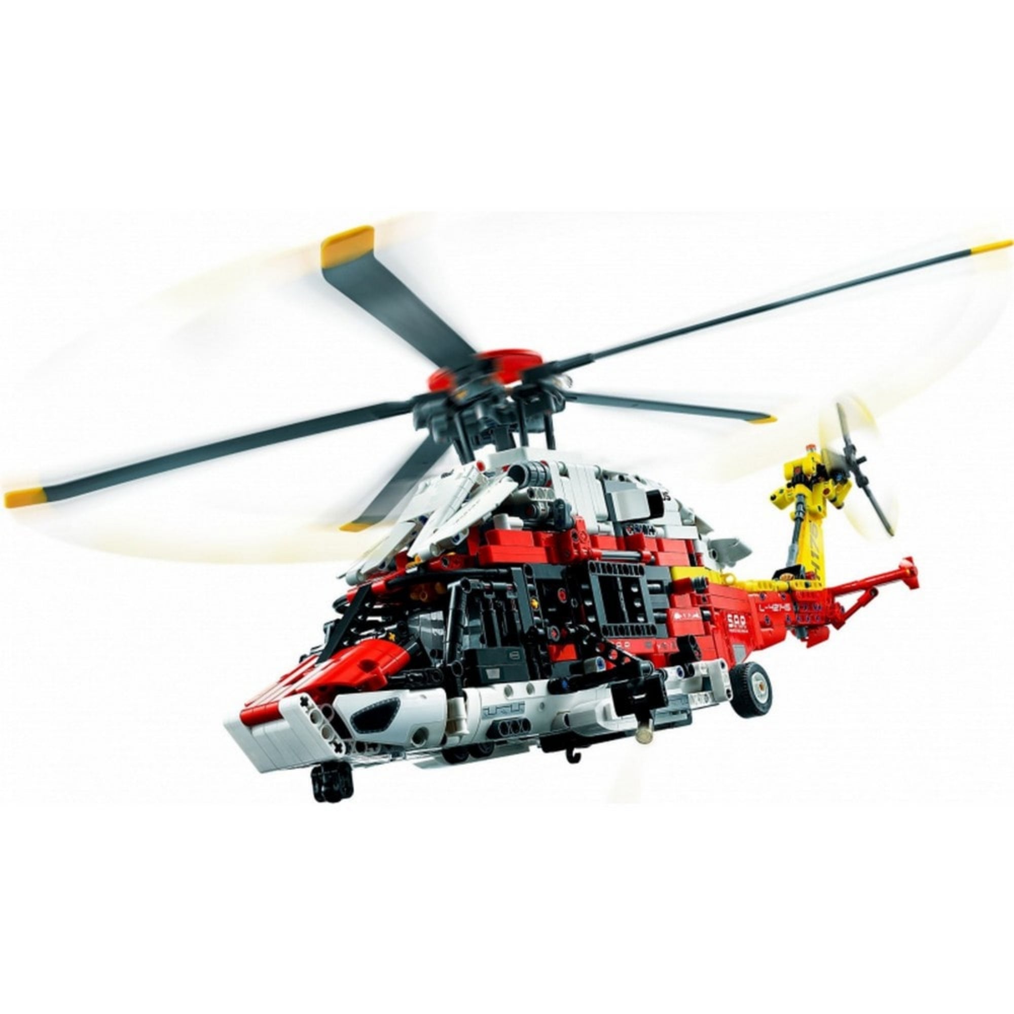 A LEGO Technic Airbus H175 mentőhelikopter elölről és kissé alulról fényképezve, mozgás közben elmosódott rotorlapátokkal, repülési pozícióban.