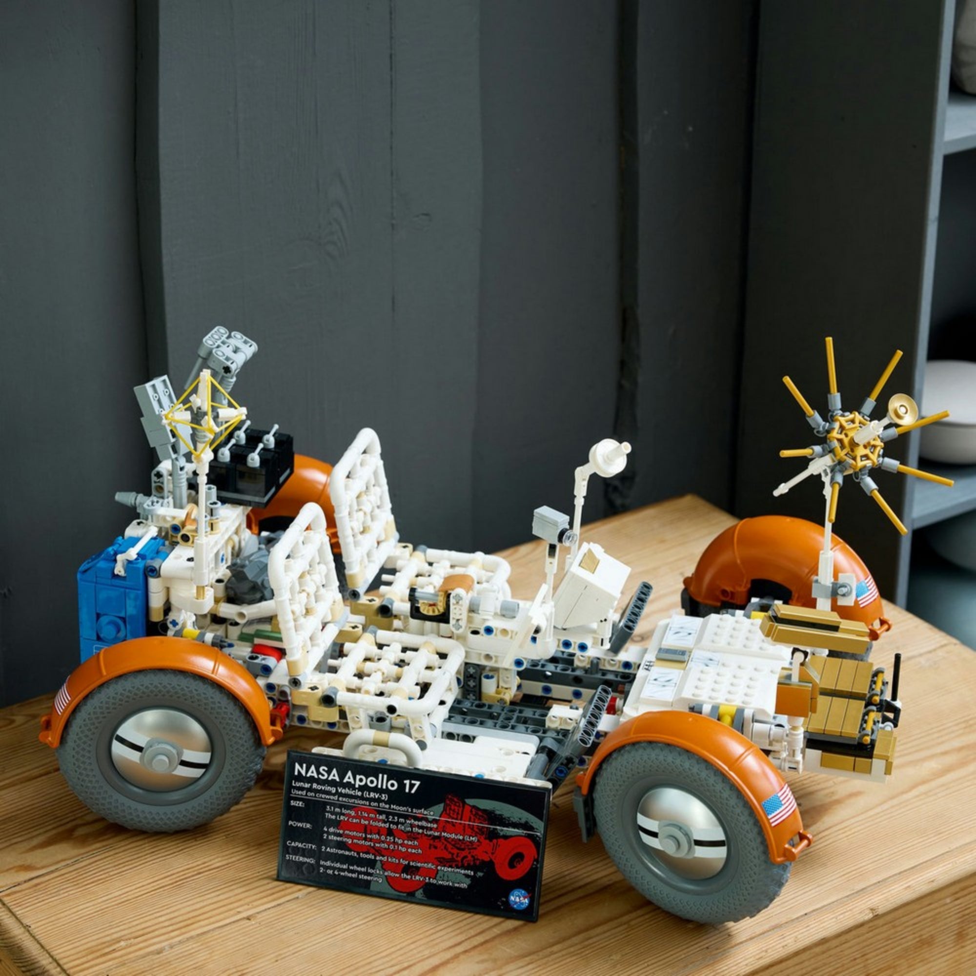„LEGO Technic NASA Apollo holdjáró jármű (42182) összerakott modellje fa felületen, jól látható részletekkel: antenna, ülések és információs tábla a jármű előtt.”