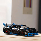 A LEGO Technic Porsche GT4 e-Performance kiállítva egy világos faasztalon, jól látható a részletes felépítése, légterelője és gumijai.